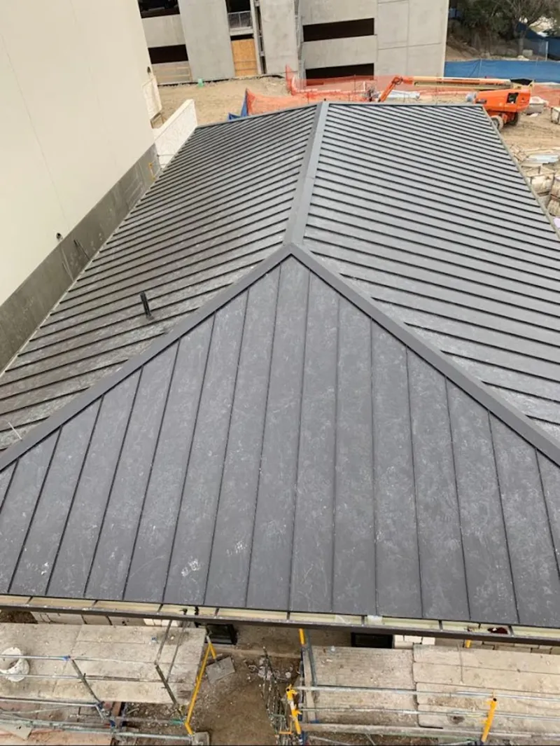 Commercial metal roof construction with crane equipment in Green
